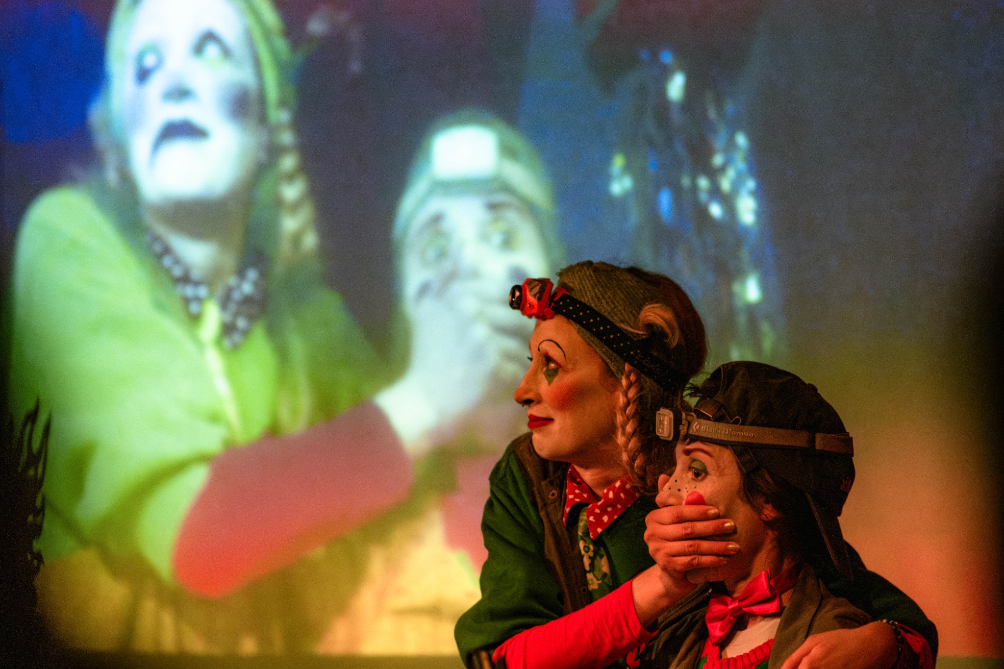 Two performers, one covering the other’s mouth